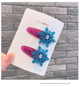 Detail of glittery blue snowflake hair clips with pink rhinestones on a white display card