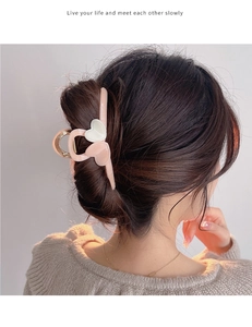 Detail view of a large milk tea heart hair claw clip styled in a low bun for women