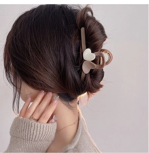 Detailed side view of a large milk tea colored heart hair claw clip on model's hair