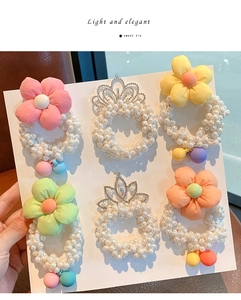 Detail of 6-piece pearl hair scrunchies set featuring floral and crown embellishments
