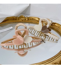 Close-up of elegant heart-shaped hair claw clips with gold metal frames on a mirror surface