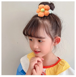 Detail of orange fabric flower hair tie with pearls on a girl's bun hairstyle