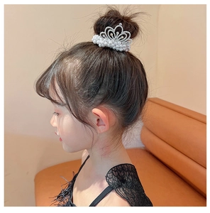 Detail of children crown hair ring with white pearls and rhinestones on a bun hairstyle