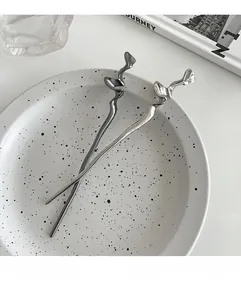 Détail d'épingles à cheveux en métal liquide torsadé argent et noir sur une assiette