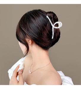 Elegant side view of a minimalist silver-tone metal hair claw clip worn in a hair bun