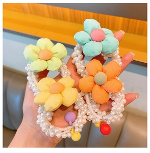 Detail of pearl beads hair scrunchie featuring pastel fabric flowers and colorful charms