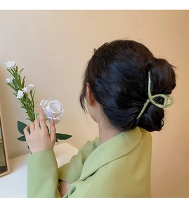 Close-up of a light green translucent shark hair claw clip styled on a low bun hairstyle