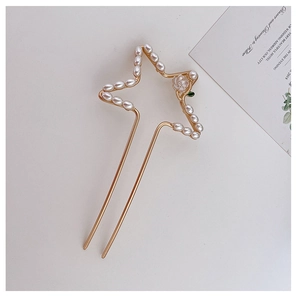 Detailweergave van een gouden U-vormige haarspeld met holle ster en parels