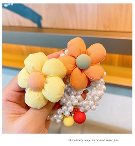 Close-up of pearl hair tie featuring fabric sunflowers and colorful hanging beads