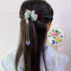 Detail einer floralen Quasten-Haarspange an geflochtenem Haar mit Harzblüten und Goldketten
