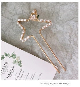 Detailopname van de gouden sterrenhaarspeld met witte parels en een roze bloemaccent