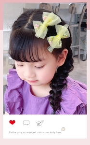 Vue détaillée de barrettes nœuds en maille jaune avec pompons colorés sur cheveux de fille