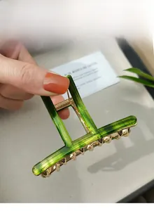 Macro detail of large green resin hair claw clip with golden alloy spring mechanism