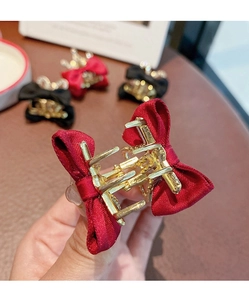 Detailaufnahme kleiner Satin-Schleifen-Haarklammern in Rot und Schwarz mit goldenen Legierung