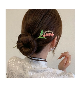 Detailed view of handmade lily of the valley hair pin styled in an elegant bun hairstyle
