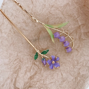 Detail of golden lily of the valley hairpins with purple enamel flowers on paper