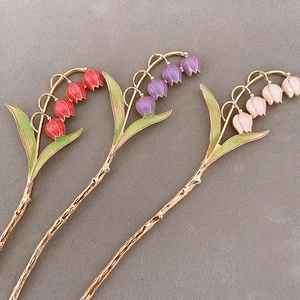 Detailed macro view of lily of the valley hair pins in red, purple, and pink enamel colors