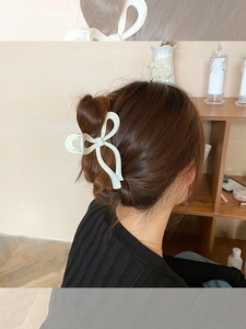 Détail d'une pince à cheveux nœud crème portée sur un chignon élégant de femme