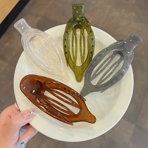 Lot de quatre grandes pinces à cheveux évidées en résine aux couleurs variées sur assiette