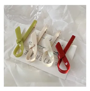 Close-up of four elegant bow hair clips in green, beige, pearl white, and retro red