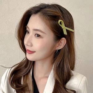 Elegant grass green bow-shaped acetate hair clip for women shown on a model