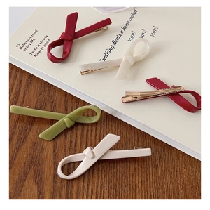 Set of five elegant knotted bow hair clips in vibrant colors on a magazine background