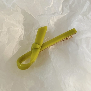 Macro shot of a minimalist olive green acetate hair clip with a stylish knotted design