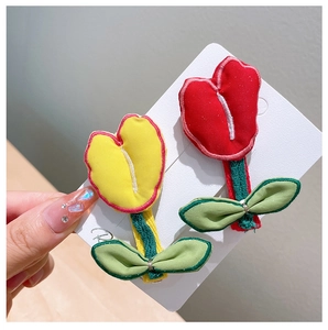 Detail of handmade embroidered tulip hair clips in red and yellow with green leaves