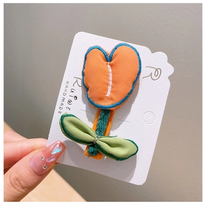 Detail of handmade embroidered tulip hair clip with orange fabric and green leaf
