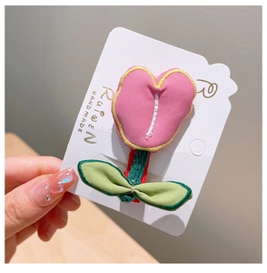 Detail of pink handmade tulip embroidery hair clip on a branded white display card
