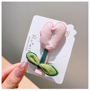 Close-up of handmade fabric tulip hair clip with pink petals and green leaves