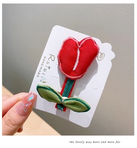 Close-up of handmade fabric tulip hair clip with red petals and green leaf detail