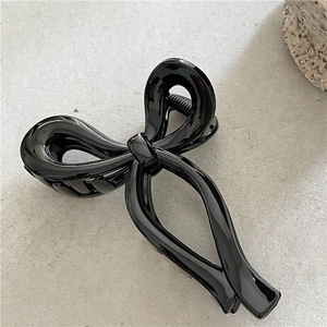 Close-up of a glossy black bow-shaped hair claw clip with a sleek acrylic finish