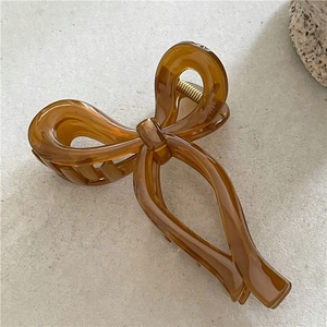 Detail of amber translucent acrylic bow hair claw clip with golden metal spring