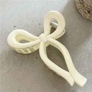 Macro view of cream bow hair claw clip with smooth resin finish and minimalist design