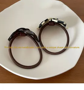 Handcrafted checkerboard and tortoiseshell hair ties on a white ceramic tray display