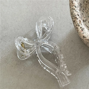 Detail shot of a transparent bow hair claw with elegant ribbon design and gold metal spring