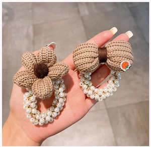 Dettaglio di elastici per capelli con fiori in maglia marrone e perline bianche