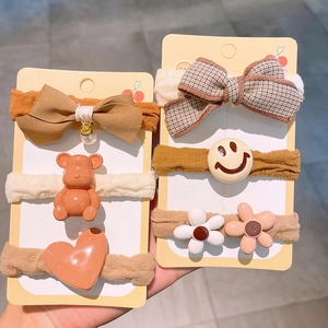 Detailansicht niedlicher Bären- und Blumen-Haargummis in Creme- und Kaffeetönen