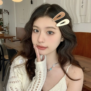 Close-up of matte brown and cream oval hair clips worn by a model in a cozy setting