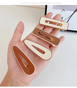 Detail view of four-piece milk tea color hair clips held by hand for hairstyle styling