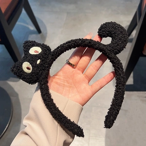 Dettaglio fascia per capelli a gatto in peluche nero con morbida consistenza in pile