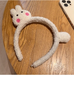 Dettaglio di fascia per capelli in peluche bianco con orecchie da coniglio e ricamo