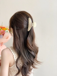 Vue arrière d'un mannequin portant une grande pince à cheveux crème pour une coiffure chic