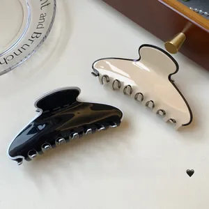 Détail de pinces à cheveux en acétate brillant noir et blanc avec bordure contrastée