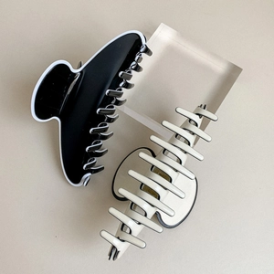 Gros plan sur deux pinces à cheveux en acétate avec des bords contrastés noir et blanc