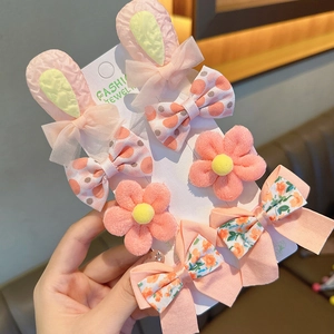 Dettaglio di un set di mollette per capelli con orecchie di coniglio e fiori per bimbe