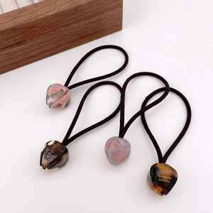 Set of four elastic hair ties featuring marbled acetate heart charms and gold engraving
