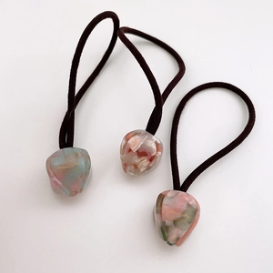 Macro detail of tulip acetate hair ties featuring elegant marble texture and gold lettering
