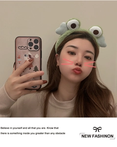 Detailed view of plush green frog headband with cute eyes worn by a model